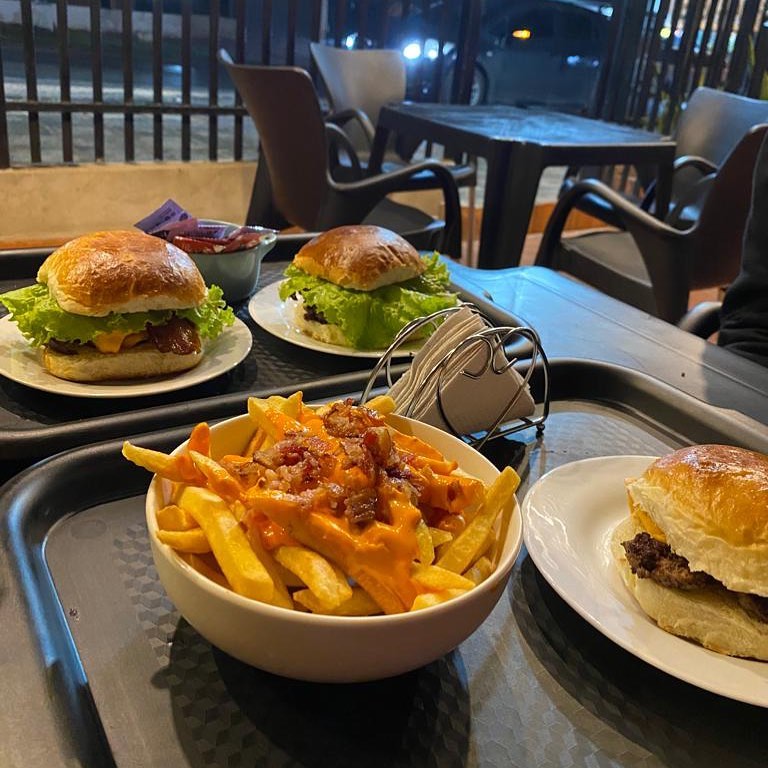 Mesa servida con hamburguesas artesanales y papas fritas crujientes en el local de Heisenburguer.